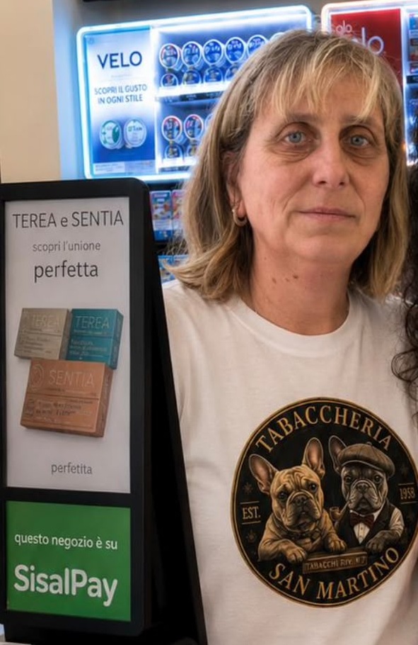 La titolare della tabaccheria che sorride dietro al banco